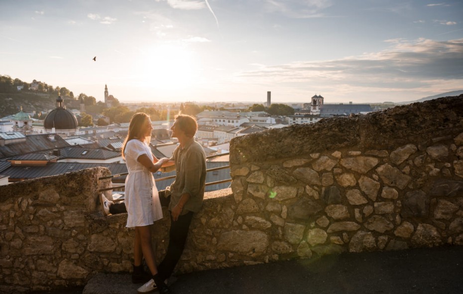 Paar genießt den Sonnenuntergang  mit Blick auf die Dächer von Salzburg.