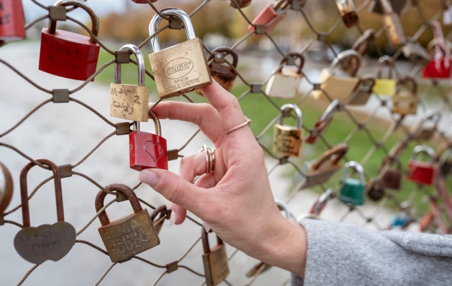 A hand attaching a personalized love lock to a bridge railing in Salzburg.